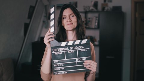  A beautiful girl holds a Clapperboard in her hands. Claps. Clicks. Winks at the camera. Flirting, flirting. The movie has started! The beginning of filming! Action. Slow Motion