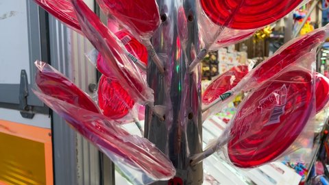 Rows of red lollipops wrapped in cellophane sticking out from a metal rod.