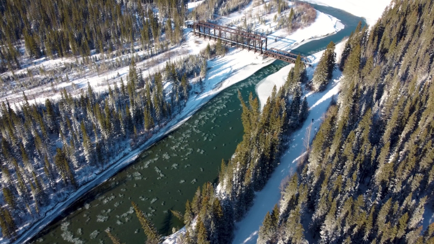 Aerial panorama view of Bow River valley forest in winter. Snowcapped Canadian Rockies mountain range beautiful scenery. Canmore Engine Bridge. Banff National Park. Alberta, Canada. Royalty-Free Stock Footage #1089884799