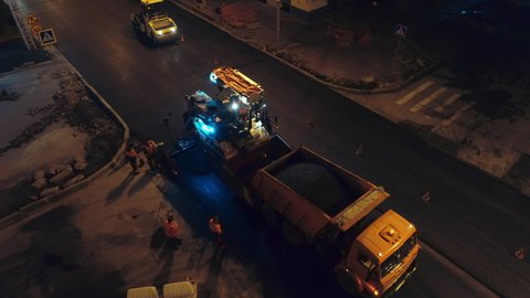 Aerial view. Preparation for unloading the asphalt concrete mixture into the asphalt paver from a dump truck. Road rollers are laying asphalt. Road repair in the city. Road workers. 