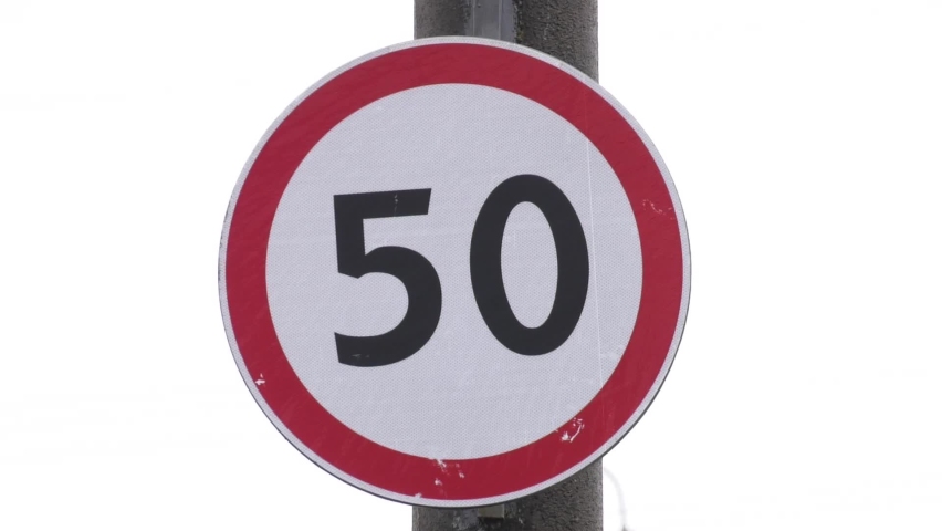 Round speed limit road sign on mountain road.  Speed limit sign in the countryside on a summer evening. The speed limit is 50 km.h on a gravel road. Speed limit traffic sign on the road. Royalty-Free Stock Footage #1089885643