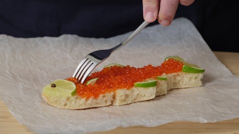 Sandwich with red caviar in shape of fish with lemon in plate on table. Eating healthy food concept slow motion. Tasting sandwiches bread  toast with salmon caviar salted roe. Fish dish. Sea food