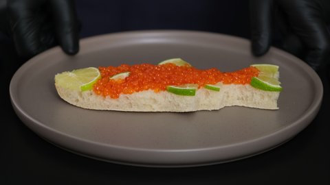 Sandwiches with salmon caviar salted roe in plate chef put on table. Sandwich with red caviar in shape of fish with lemon. Expensive healthy food concept close-up slow motion. Fish dish. Sea food