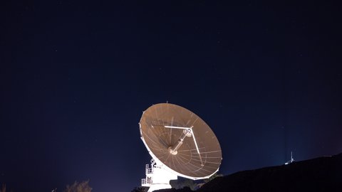 A night timelapse of a moving satellite with stars passing behind 