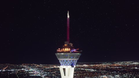Stratosphere Tower, Las Vegas USA, Apr. 2022. Cinematic panoramic aerial around the STRAT hotel with attractions and rides on SkyPod observation deck with epic views on night Las Vegas under stars