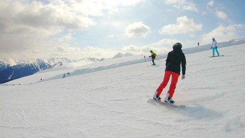 Woman Snowboarding Fast on Ski Slope Mountain. Snowboarder having fun snowboarding backcountry on a sunny winter day in snowy mountains.