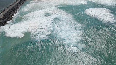 Ocean Waves Rolling Onto The Shore And Seawall Of Duranbah Beach With Surfers In Summer. Flagstaff Beach In Tweed Heads, NSW, Australia. aerial drone