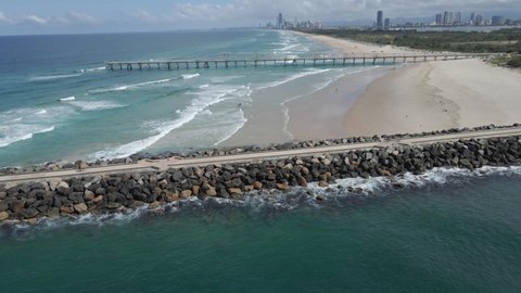 Seawall And Fishing Pier At The Beach In Summer. The Spit Gold Coast And Sand Bypass Pumping Jetty In Queensland, Australia. aerial sideways