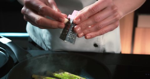 The chef rubs the garlic on a small grater