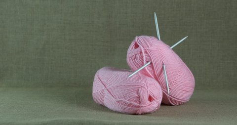 Pink wool threads. A view of pink woolen ball with needles on the table.