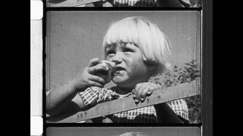 1950s Ontario, CA. A young child with blond hair takes a bite our of a freshly picked apple. The kid enjoying the fall apple harvest. 4K Overscan of Archival Newsreel
