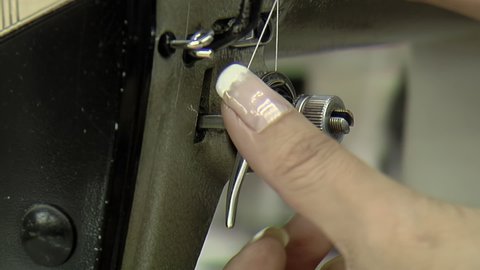 Woman Threading a Sewing Machine Needle, A Sewer Threading a Needle in the Sewing Machine. Close Up.