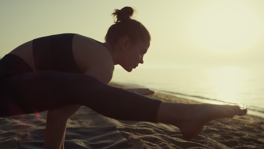 Proffesional yoga woman leaning on hands practicing firefly position at sunset close up. Sporty girl training balance on beach summer evening. Focused sportswoman making tittibhasana outdoor.
