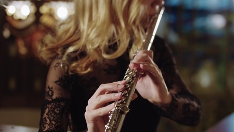 Adult blonde woman playing flute on a background of stained glass windows