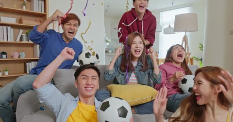 slow motion of happy asian friends cheer watching live streaming soccer game clapping high five while scoring goals with falling colorful confetti