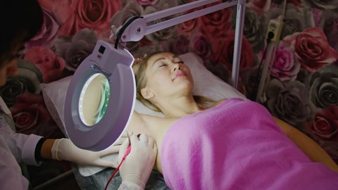 Woman patient lies on beauty couch. The girl is doing the electric electrolysis epilation, hair removal procedure. 4k prores 422.