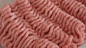Closeup view 4k video footage of fresh raw minced or grounded organic turkey meat isolated in white plastic package spinning around slowly. Pink and white meat  ingridients texture