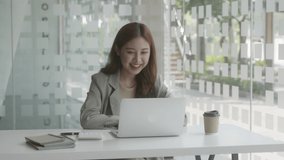 Video of a young beautiful business woman is having video call for online meeting and presentation her woks with smiling face and laughing. Soft mood and soft focus. 