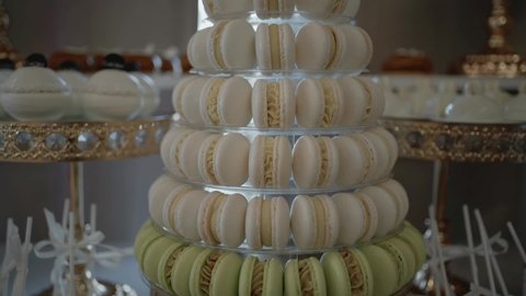 Colorful macarons on the crystal plate. Candy bar at the wedding reception. Delicious desserts. Beautiful decorations.