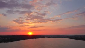 Sun sets over the horizon and the twilight sky is reflected in the ripples of the lake. Footage from a bird's eye view. Ukraine, Europe. Cinematic drone shot. Filmed in UHD 4k video. Beauty of earth.