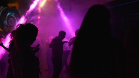 Mariupol, Ukraine - 15 June 2019. People are dancing in Barbaris night club lit by show lights. Silhouettes of men and women partying on dance floor in slow motion. Ordinary open entry weekend party.