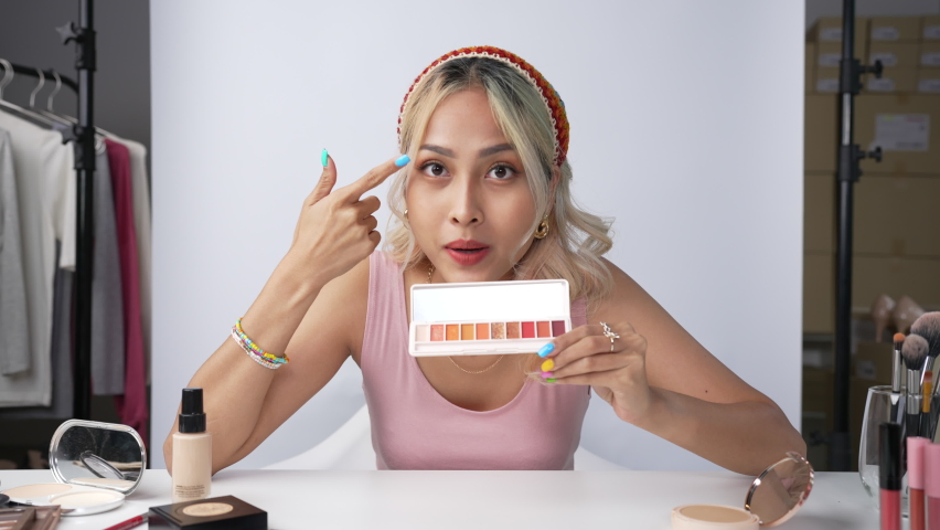 Young beautiful Asian woman and professional beauty make up artist vlogger or blogger recording makeup tutorial to share on website or social media. Business online influencer on social media concept.