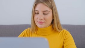 Beautiful Ukrainian girl working on laptop. Video portrait of young white woman doing distant work online. Focused freelancer person typing text on notebook computer at home 