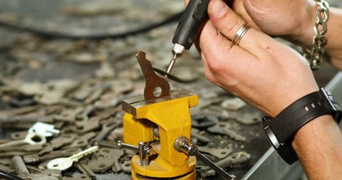 Locksmith in workshop makes new key, use grinding engraving machine, production of duplicate metal key.
