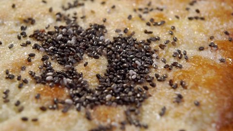 Pita bread with falling organic chia seeds. Sugary flatbread texture close up. Macro. Rotation. Slow motion