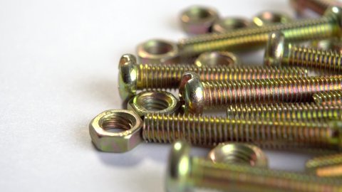 Shiny metal bolts and nuts on white. Threaded hardware for fastening. Mechanical tools. Macro. Rotation