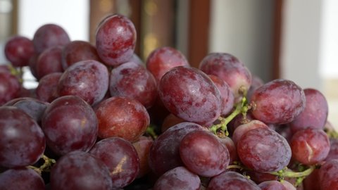 Close-up view 4k video footage of red seeded organic grapes raisins. Fruits of Chile. Bunch of fresh organic grapes isolated on blurry home interior background