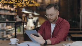 Waist up portrait view of the skillful programmer typing at the tablet while working at the cafe. Man using gadget with light smile. Technologies and people concept - Powered by Shutterstock - Get 15% off with code: PIKWIZARD15