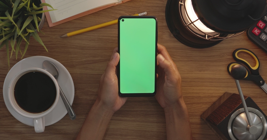 Top View Woman Uses Thumb Touching On Green Screen Of Smart Phone. Hobby Table Background. Chroma Key. Mobile Phone With Green Screen. Royalty-Free Stock Footage #1089914867
