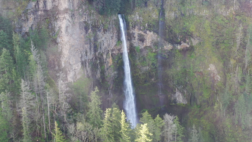 Clouds drift over a beautiful waterfall plunging over 500 feet into the Columbia River Gorge, Oregon. This narrow canyon, with the Columbia River flowing through it, separates Oregon and Washington.