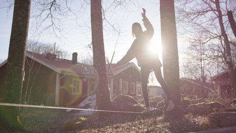 LENS FLARE SLO-MO - Beautiful dreamy image of a female slack liner walking the strap