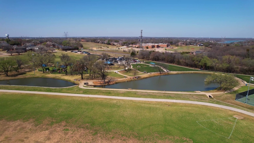 Aerial footage approaching Unity park in Highland Village Texas and flying over two ponds.