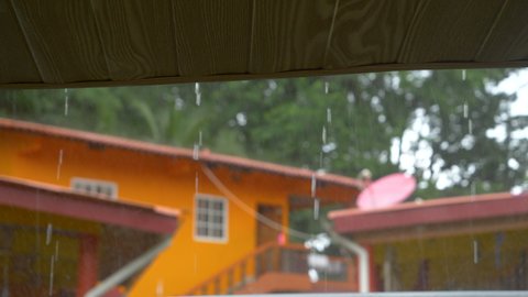 STILL SHOT, CLOSE UP: View of pouring rain from under the roof . Overlooking tropic cloudburst and dripping raindrops. Moody weather during wet season at exotic location.