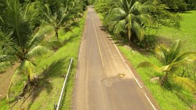 AERIAL: SUV car avoiding big asphalt holes while driving along road in tropics. Winding vehicle bypassing asphalt holes in exotic countryside. Damaged infrastructure in tropical third world.