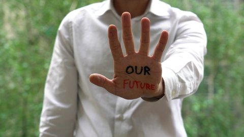 businessman hands with written in our hands is our future - protest and message against climate change and war - flash mob activism against crisis - self-esteem and ability to achieve one's goals