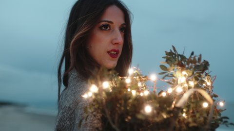 Sweet girl squeezes to herself bouquet of flowers with lights