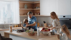 Happy family cooking pasta together stand in the kitchen. Hurry up. Mother, father, boy and girl. Preparing salads, cutting avocado. Slow motion - Powered by Shutterstock - Get 15% off with code: PIKWIZARD15