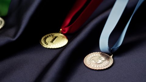 Gold, silver and bronze medals with ribbons on black background close-up. First, second and third place. Award and victory, winning the championship. 