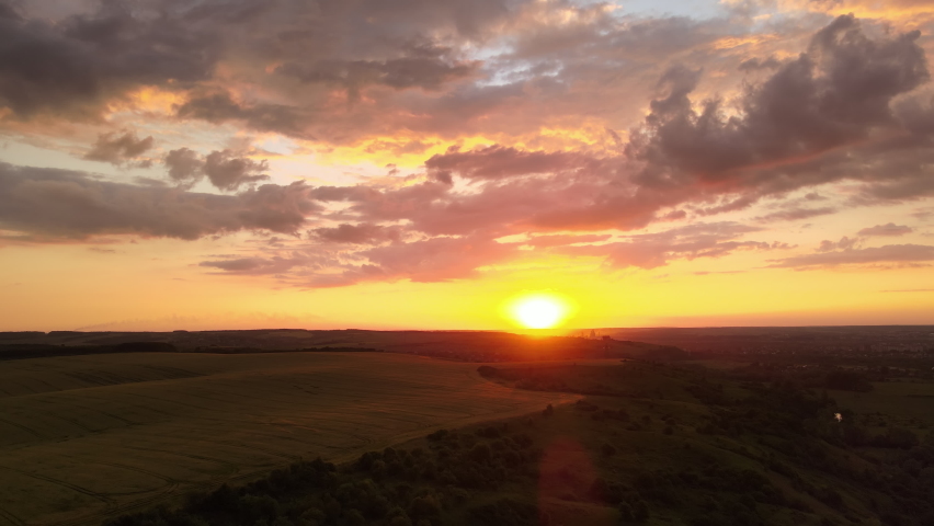 Aerial landscape view of yellow cultivated agricultural field with ripe wheat on vibrant summer evening
