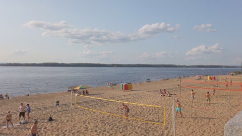 Samara, Russia - circa April, 2022: A group of people playing beach volleyball on the sand on the bank of a big river