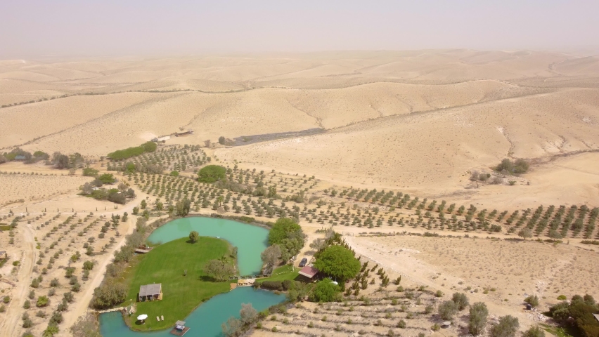 Flying backward over Negev Desert with a park and small lake before a time of sand storm