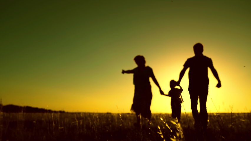 Mom dad son family walk. Happy family runs in park at sunset. Teamwork. Parents and son run at sunset. Silhouette of happy family in park. Children are running. Silhouette of happy family in park
