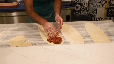 Turkish chef in the hotel puts meat stuffing on the dough
