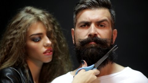Cutting long beard. Bearded man in a barbershop. trendy cut beard. shaving beard. Barber Shop procedures. Woman cuts hair with scissors. Man with long beard, mustache and stylish hair.