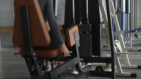 female doing legs, hips, buttocks abduction exercises using inner thigh machine, powerlifting weights adduction equipment in sport club fitness gym. pumping muscles for fitness healthy body