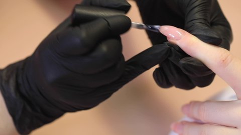 Manicure process in a beauty salon. The manicurist paints the nail with varnish.